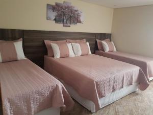 um quarto com 2 camas com lençóis cor-de-rosa e brancos em Hotel Contorno Sul em Curitiba