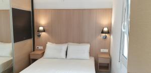 een slaapkamer met een bed met witte kussens en 2 lampen bij Studio Marevi in Elounda