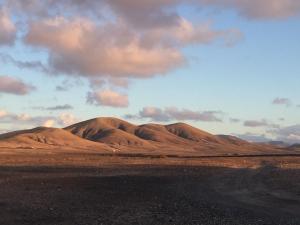 a desert with brown hills and a cloudy sky at Casa Vega in El Cotillo +6 photos