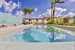 a swimming pool with blue water and palm trees at Newport House Playa Boutique Hotel in Playa del Carmen