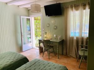 a bedroom with a desk and a television on the wall at Logis Hotel Restaurant Hostellerie de la Tour in Fontvieille