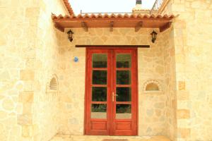 a red door on the side of a stone building at Piges Hotel in Gliki
