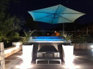 a patio with a table with an umbrella and a pool at Villa Aurelia in Žman