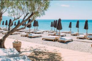 a beach with umbrellas and lounge chairs and the ocean at BETTY'S HOUSE in Pythagoreio