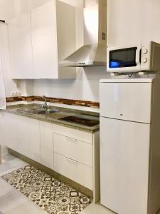 cocina blanca con fregadero y microondas en Centro Histórico Mezquita Judería La Preferida en Córdoba