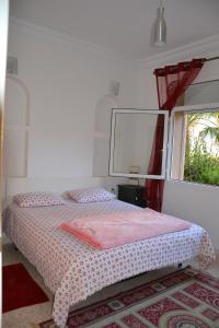 Schlafzimmer mit einem Bett mit rosa Bettwäsche und einem Fenster in der Unterkunft VILLA DE STANDING --PISCINE - MER - BOULODROME - TENNIS in Tiznit