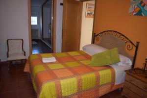 ポソ・アルコンにあるAlojamientos Rurales la Lomaのベッドルーム1室(黄色とオレンジの毛布付きのベッド1台付)