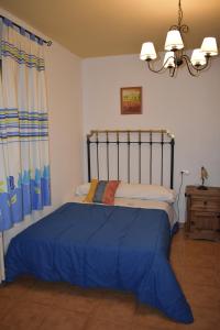ポソ・アルコンにあるAlojamientos Rurales la Lomaのベッドルーム1室(青い毛布付きのベッド1台付)