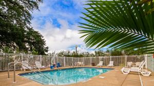 a swimming pool with chairs and a fence at Key West Inn - Fairhope in Fairhope
