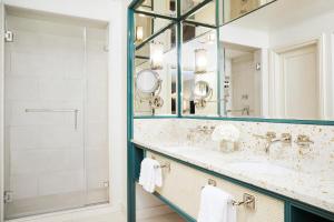 a bathroom with a mirror, sink, and bathtub at Four Seasons Resort Palm Beach in Palm Beach