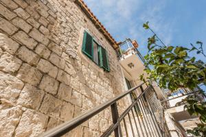 a stone building with a green window and a fence at Kovacic Rooms in Split