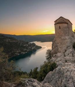an old stone tower on top of a mountain overlooking a lake at Apartaments La Pertusa in Corçà