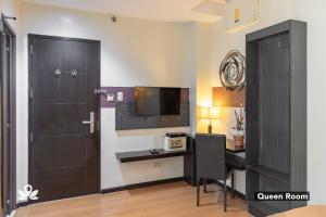 um quarto com uma secretária, uma porta e uma televisão em Lorenzzo Suites Makati em Manila
