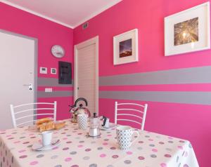 ein Esszimmer mit einem Tisch und einer rosa Wand in der Unterkunft Il Sopracciglio Suites - Pink Apartment in Cassino