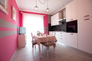 eine Küche mit einem Tisch und einer rosa Wand in der Unterkunft Il Sopracciglio Suites - Pink Apartment in Cassino