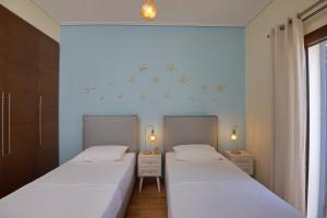 2 Betten in einem kleinen Zimmer mit weißen Wänden in der Unterkunft Lidromi Home (Blue) in Alonnisos Altstadt