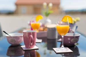 two glasses of orange juice and cups on a table at Apartments Braut Krk in Krk
