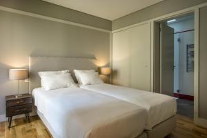 a bedroom with a large white bed with two lamps at Porto Republica Apartments in Porto
