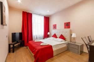 a bedroom with a bed with red curtains and a television at Mini Hotel Pomestie in Saint Petersburg