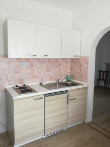 uma cozinha com armários brancos e um lavatório em Biohof Sattler em Etmissl