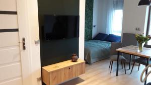 uma sala de estar com uma cama, uma mesa e uma televisão em Apartament na Piernikowym z miejscem postojowym em Toruń