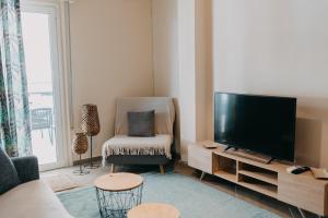 a living room with a flat screen tv and a chair at BEST HOUSE, DECK APRTM., OLD PORT OF PATRAS in Patra