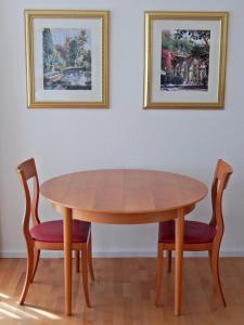 a wooden table with two chairs and two pictures on the wall at FREE Apartment - Bei der Markthalle in Reutlingen