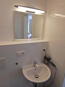 a white bathroom with a sink and a mirror at FREE Apartment - Bei der Markthalle in Reutlingen