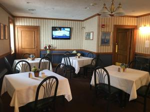 a dining room with tables and chairs and a tv at The Island House Hotel in Port Clinton