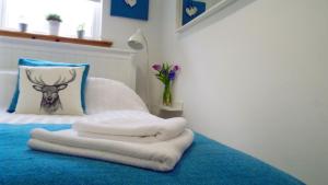 Una cama con toallas y una almohada con un ciervo. en Flat 14d Bayhead, en Stornoway