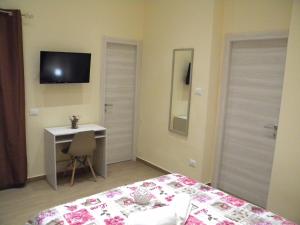 een slaapkamer met een bed, een bureau en een televisie bij La Casetta del Viale 13 in Palermo