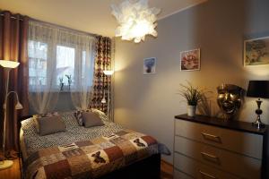 a bedroom with a bed and a dresser and a window at KGHN Apartments Tkacka 28 in Szczecin