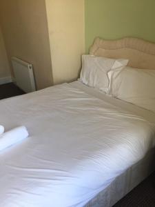 een bed met witte lakens en kussens in een kamer bij Gateway Lodge in Cleckheaton