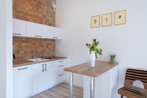 een keuken met witte kasten en een houten tafel bij PROVENIR HOME STRZELECKA 25 in Poznań