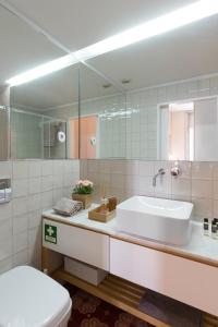 ein Badezimmer mit einem Waschbecken, einem WC und einem Spiegel in der Unterkunft GET a golden and flower flat in Porto