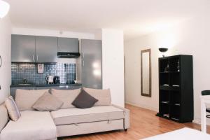 a living room with a white couch and a kitchen at Lauriston Nice Studio in Paris