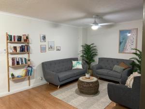 a living room with two couches and a book shelf at Burleigh Gardens North Hi-Rise Holiday Apartments in Gold Coast