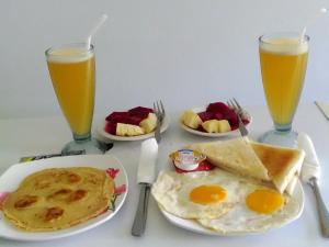 a table with plates of breakfast food and two glasses of orange juice at Gula Juruh Beach Front in Amed