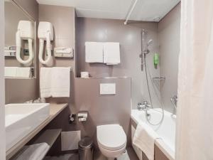 La salle de bains est pourvue de toilettes, d'un lavabo et d'une douche. dans l'établissement New Orient Hotel, à Paris