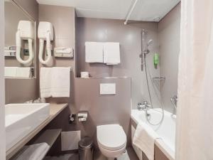 ein Bad mit einem WC, einem Waschbecken und einer Dusche in der Unterkunft New Orient Hotel in Paris