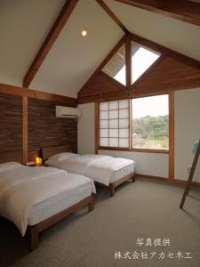 two beds in a room with a window at Shiraishi Island International Villa in Kasaoka