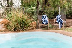 duas cadeiras com toalhas sentadas ao lado de uma piscina em Saltbush Retreat em Longreach