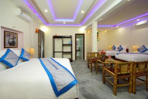 ディエン・バンにあるHoi An Blue Seaside Homestayのベッド2台とテーブルが備わるホテルルームです。