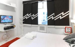 1 dormitorio con 1 cama blanca y TV en Flat a Beira Mar - Copacabana, en Río de Janeiro