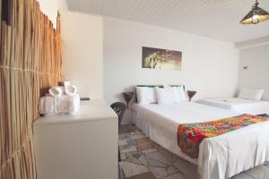 a white room with two beds and a table with a bed sqor at Pousada Vila Nalu in Praia do Frances