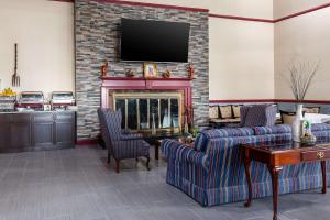 a living room with a fireplace with two chairs and a tv at Clarion Inn Falls Church- Arlington in Falls Church