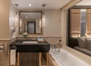 a bathroom with a sink and a tub and a mirror at Henann Garden Resort in Boracay