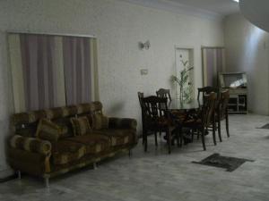 sala de estar con sofá, mesa y sillas en Sunrise Guest House Multan, en Multán