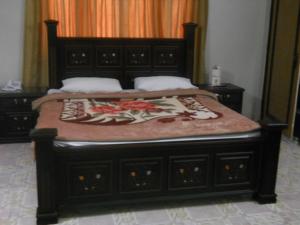 a bedroom with a bed with a wooden frame at Sunrise Guest House Multan in Multan