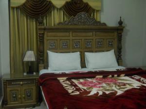 a bedroom with a large bed with a wooden headboard at Sunrise Guest House Multan in Multan